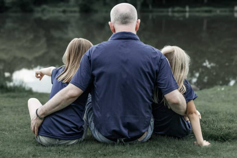 Papa avec ses deux filles au bord d'un lac